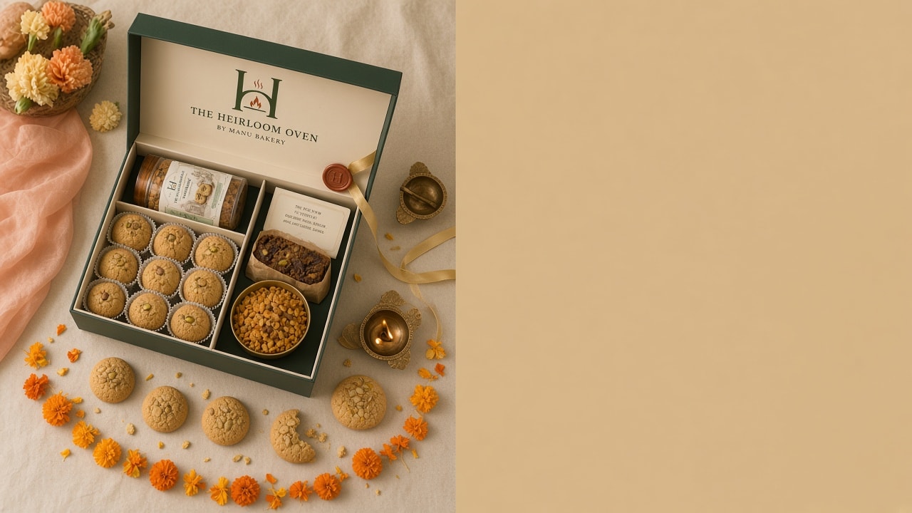 Overhead view of an open forest-green Heirloom Oven Festival box with nankhatai, marigold petals and brass diyas